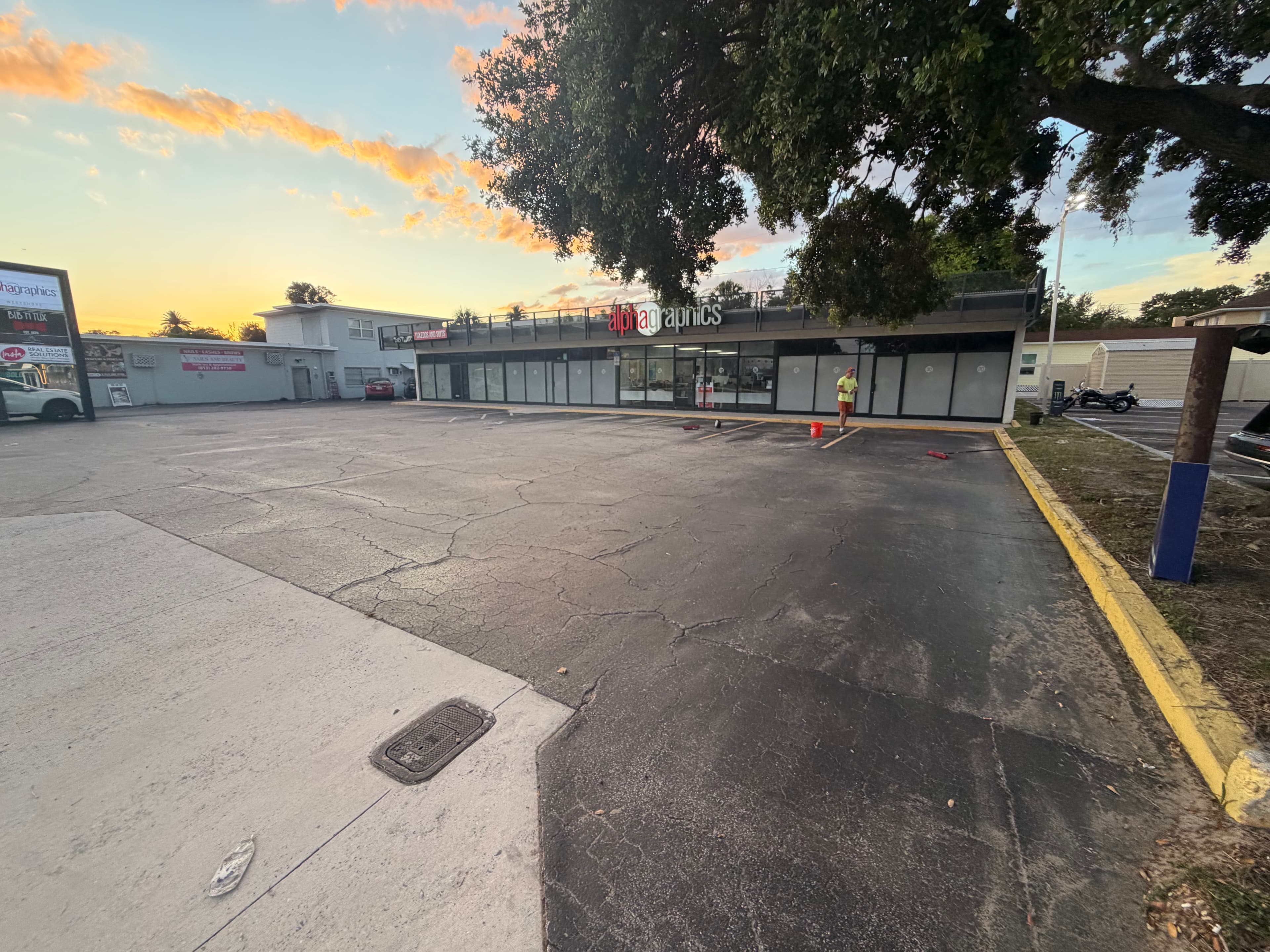 Commercial parking lot before sealcoat, showing cracked and patched asphalt