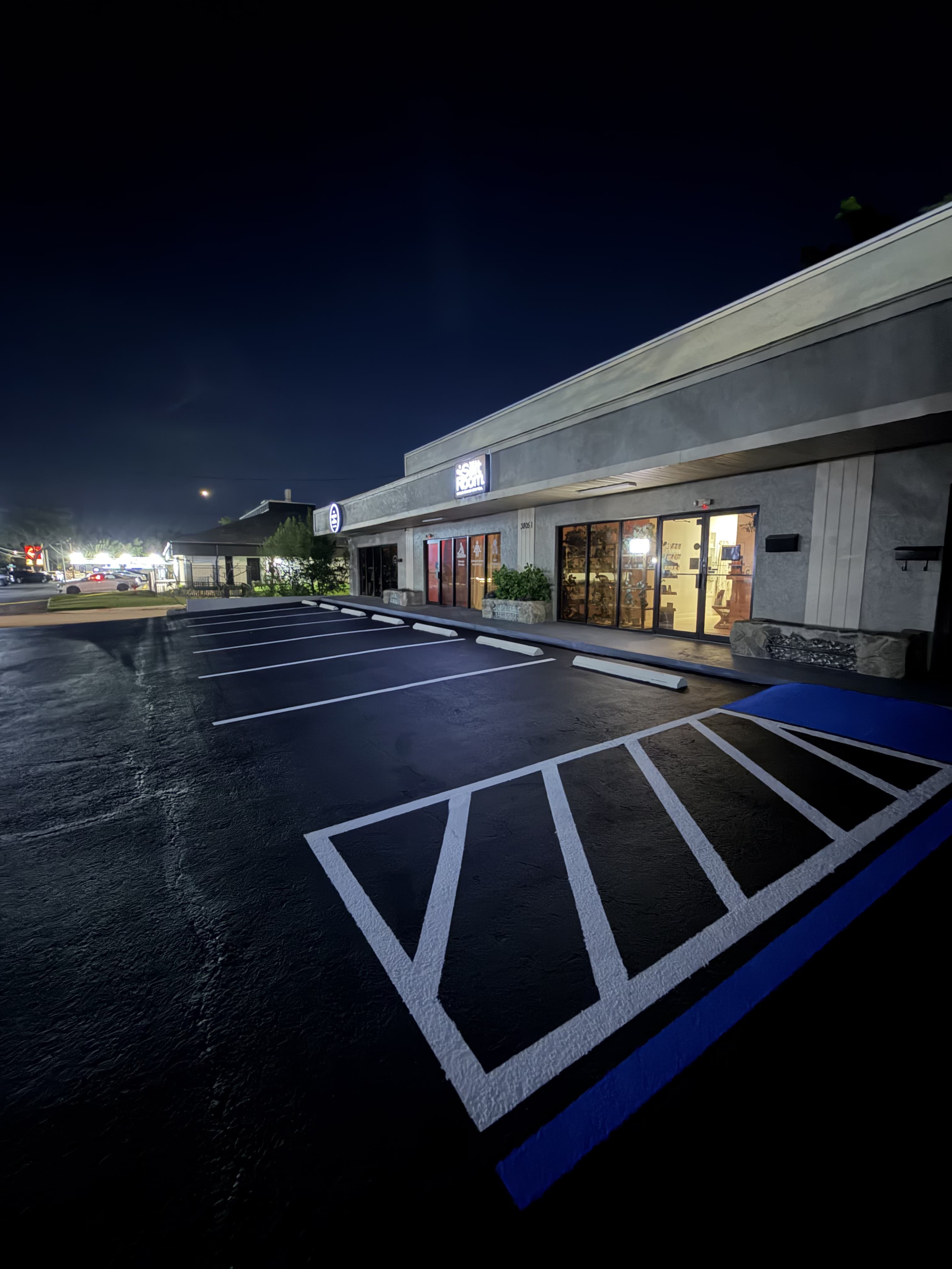 Fresh sealcoat and ADA striping on a retail plaza lot at night